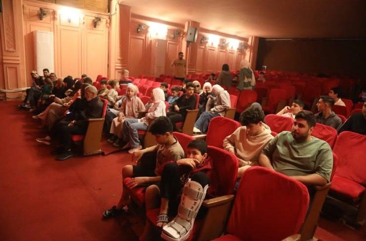 An audience seated in the red seats of the restored Le Colisée
